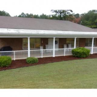 A suburban house with a spacious front porch and well-maintained lawn.