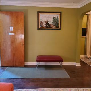 A cozy living room with a wooden door, red bench, and artwork on the wall.
