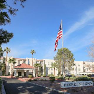 A building with an American flag, surrounded by palm trees and a sign reading 'Desert Springs.'