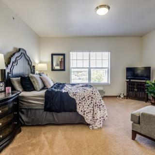 A cozy bedroom with a large bed, elegant decor, and a TV in the corner.