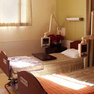 A well-lit hospital room with two neatly arranged beds and medical equipment.
