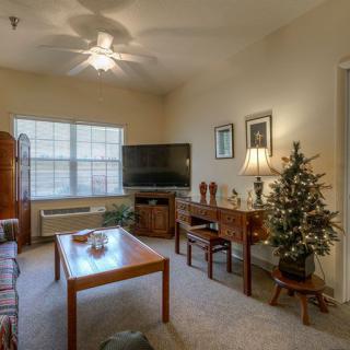 A cozy living room with a television, table, and a small Christmas tree.