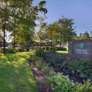 A lush landscape with pathways and a prominent sign, surrounded by trees and greenery.