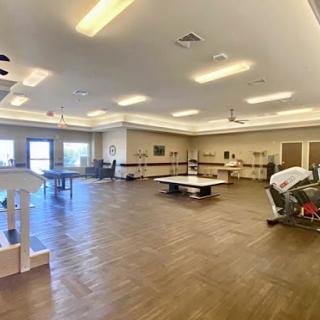 A spacious recreational room featuring wooden flooring and ample lighting.