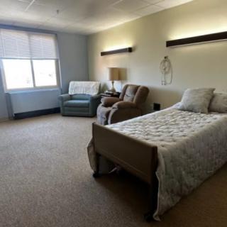 A well-furnished hospital room with a bed and seating area.