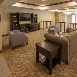 A cozy living room with a sofa, armchairs, and a television set against wooden shelving.