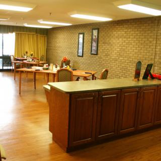A view of an office workspace with multiple desks and chairs, featuring a brick wall and wooden flooring.