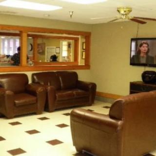 A cozy waiting room with leather chairs, a television, and a mirror on the wall.