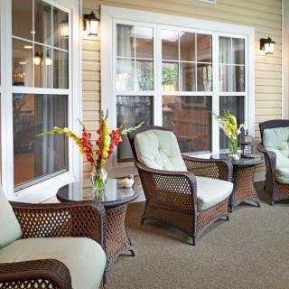 A cozy patio with comfortable wicker chairs and small tables adorned with flowers.