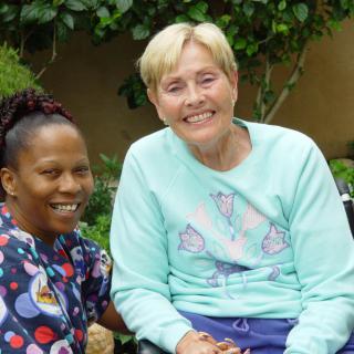 Two women smiling together in a garden setting.