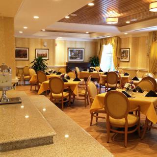 An elegant dining area set with tables and chairs in a warmly lit restaurant.