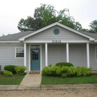 A small suburban house with a front porch and neatly trimmed bushes.