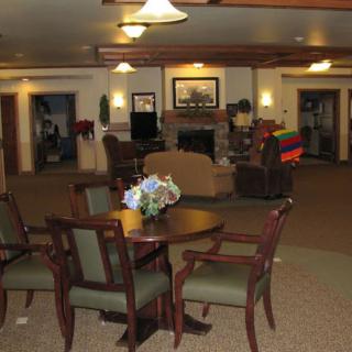 A cozy lobby area with a wooden table and chairs, soft lighting, and decorative elements.