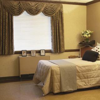 A neatly organized bedroom with a single bed, elegant curtains, and simple decor.
