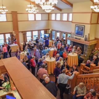 A large group of people socializing at an indoor gathering or reception.