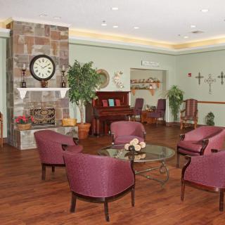 A cozy lounge area with a fireplace, seating, and piano.