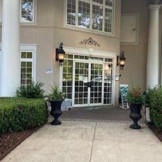 Entrance of a building with columns and landscaped shrubs.
