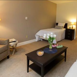 A cozy bedroom featuring a single bed, a coffee table with decorative items, and soft lighting from a bedside lamp.