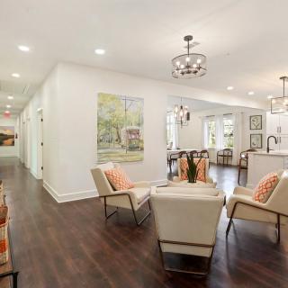 A modern living room with an open floor plan, featuring stylish seating and wood flooring.