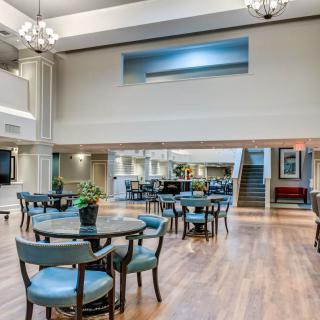 Spacious lobby area with tables and chairs, featuring modern decor and natural lighting.