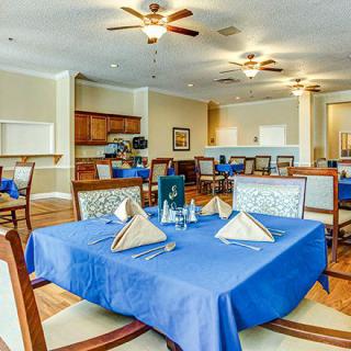 A neatly arranged dining area with blue tablecloths and elegant place settings.