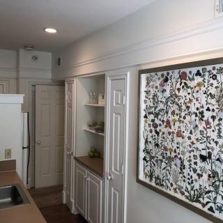 A modern kitchen featuring white cabinets and an abstract painting on the wall.