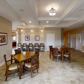 A spacious dining area with wooden tables and chairs, adorned with ceiling lights and wall artwork.