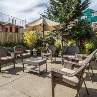 A cozy outdoor patio with wicker furniture set and a large sun umbrella in a sunny garden setting.