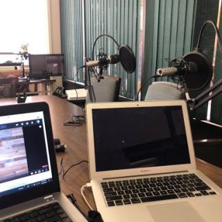 A podcast recording setup featuring laptops and microphones in a spacious workspace.