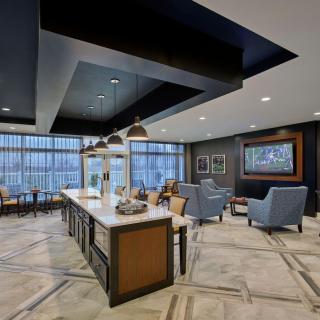 A modern lounge area featuring comfortable seating, pendant lighting, and large windows.