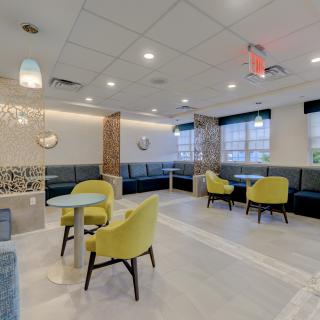 A modern lounge area with yellow chairs, tables, and stylish lighting.
