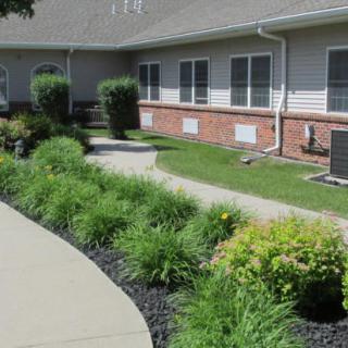 A well-maintained garden with a walkway and surrounding greenery in front of a building.
