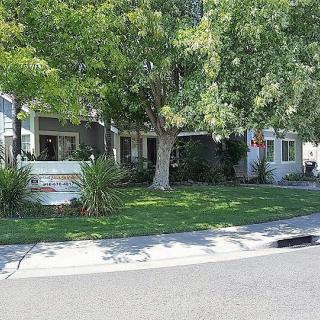 A suburban home with a well-maintained lawn and large trees.