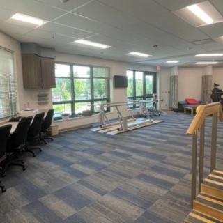 A spacious rehabilitation center with therapy equipment and workstations.