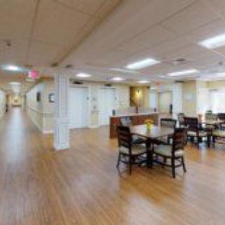 A spacious interior hallway with a dining area featuring tables and chairs, set on a wooden floor.