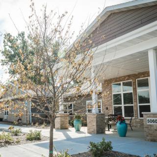 A sunny view of a building entrance with trees and a clear pathway.
