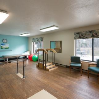 A spacious rehabilitation therapy room equipped with exercise tools and a stair setup.