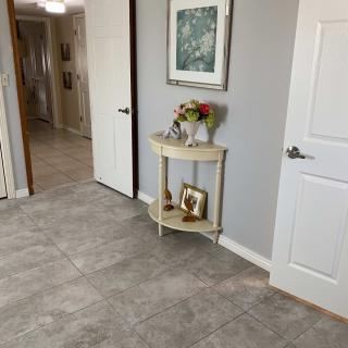 A tidy hallway with a small table displaying flowers, photographs, and artwork on the wall.