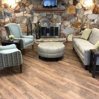 A cozy living room with a stone fireplace, wood flooring, and comfortable seating arrangement.