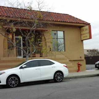 A white car parked in front of a building with a red-tiled roof.