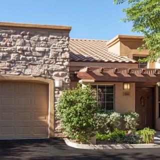 A picturesque residential home featuring a stone facade and garage, surrounded by landscaped greenery.