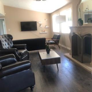 A modern living room with black leather furniture and a fireplace.