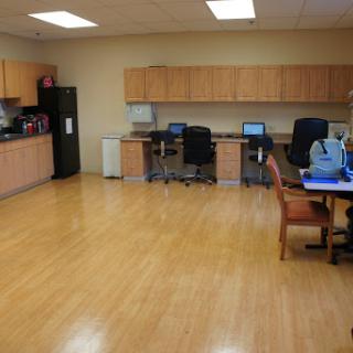 A spacious office area featuring a kitchenette, workstations with computers, and comfortable seating.