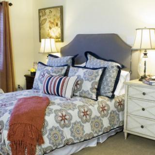 A cozy bedroom with a neatly made bed, decorative pillows, and ambient lighting from bedside lamps.