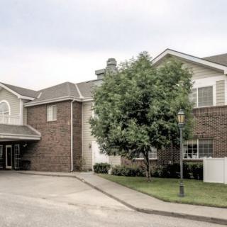 A suburban residential building with a brick exterior and a tree in the front.