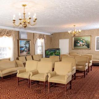 A conference room with arranged seating, chandeliers, and wall paintings.