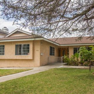A suburban single-story house with a well-maintained lawn and trees.