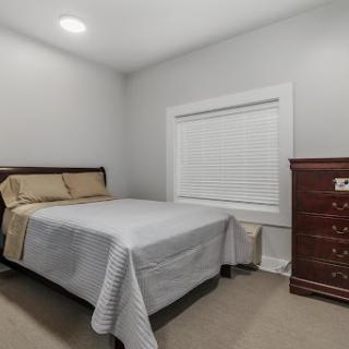 A cozy and minimalist bedroom featuring a neatly made bed and a classic dresser.
