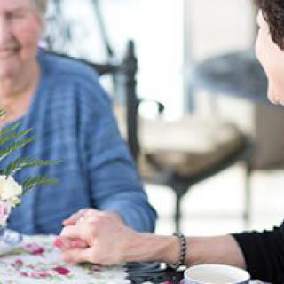 Two people sharing a moment of support and conversation at a table.