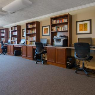 A modern office space featuring multiple desks equipped with computers and bookshelves.